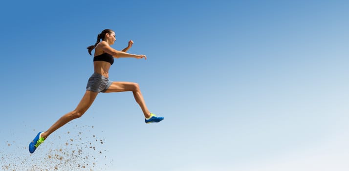 Profile view of sportswoman jumping  against scenic view of blue sky
