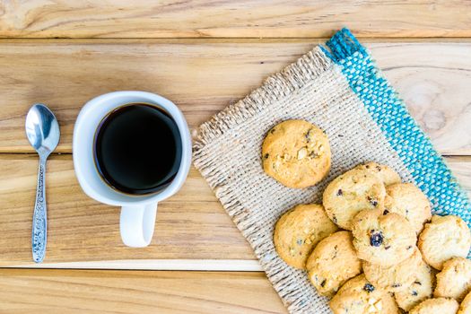 Black coffee and cookies on sack on wooden background