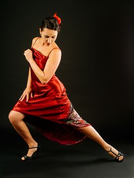 Photo of a beautiful woman dancing the tango over dark background.