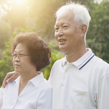 Portrait of healthy Asian seniors retiree couple looking away at outdoor nature park, morning beautiful sunlight background.