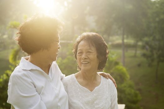 Portrait of healthy Asian seniors mother and daughter having fun at outdoor nature park, morning beautiful sunlight background.