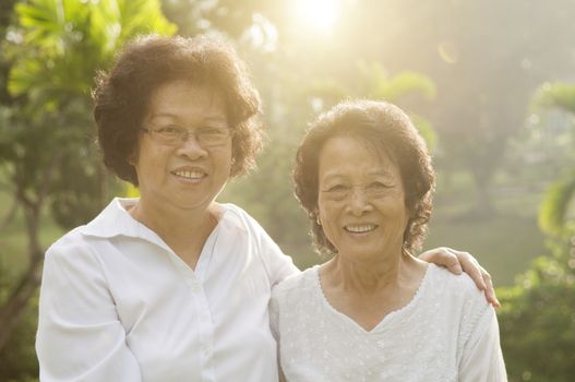 Portrait of healthy Asian seniors mother and daughter smiling at outdoor nature park, morning beautiful sunlight background.