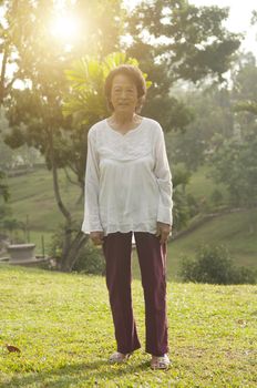 Portrait of healthy happy Asian senior woman walking at outdoor nature park, morning beautiful sunlight background.