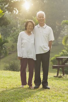 Portrait of healthy and happy Asian seniors retiree couple walking at outdoor nature park, morning beautiful sunlight background.