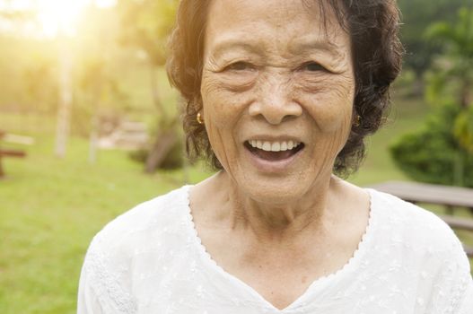 Portrait of healthy happy Asian senior woman laughing at outdoor nature park, morning beautiful sunlight background.