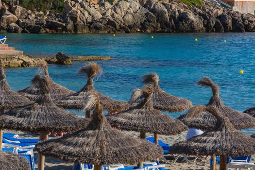 Blue sea and sand beach with sun loungers and parasols.