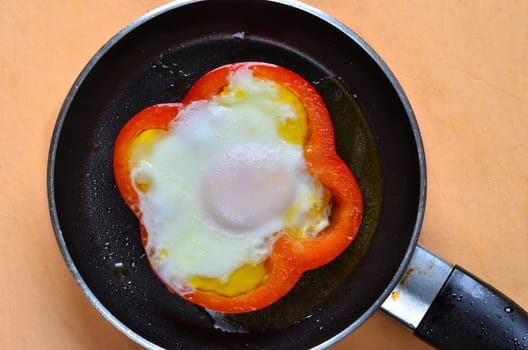 Fried egg inside slice of red pepper. Macro image.