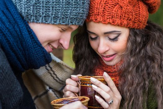 young couple in love with a cup of coffee in the autumn garden