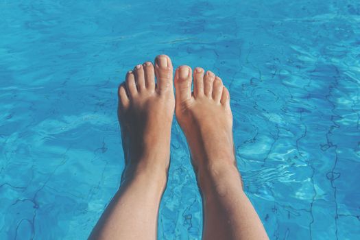 naked female legs on a background of blue water.