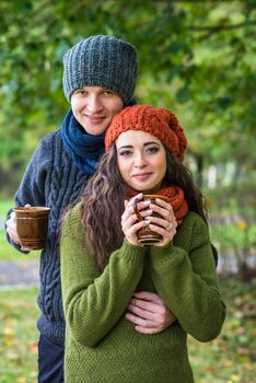 young couple in love with a cup of coffee in the autumn garden