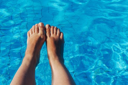 naked female legs on a background of blue water.