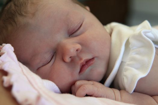 Sleeping newborn baby in the arms of mother in hospital