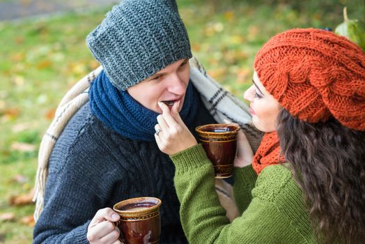 young couple in love with a cup of coffee in the autumn garden