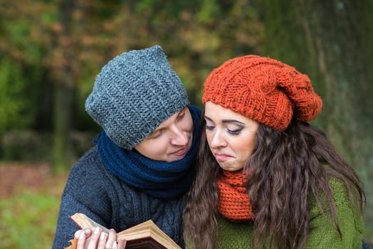 loving couple reads a book in the autumn garden