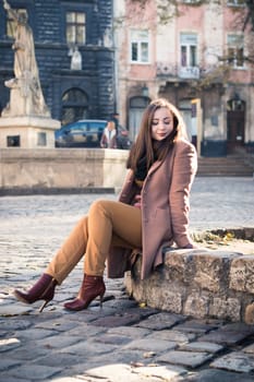 pretty girl sits on a rock in the city in the morning