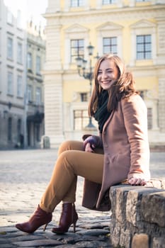 pretty girl sits on a rock in the city in the morning