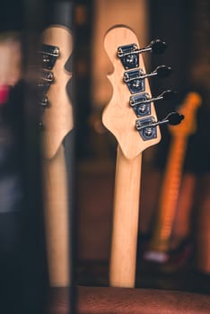 Detail of Bass Guitar Head and Neck with Reflection. Other Guitar Necks in Background. Vintage Filter. Bass Guitar Still Life. Music Background.