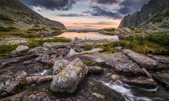 Mountain Lake Above Skok Waterfall with Rocks in Foreground at Sunset. Mlynicka Valley, High Tatra, Slovakia.