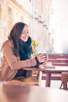 beautiful girl drinking coffee in a cafe on the street