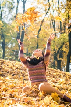 beautiful girl in autumn Park keeps yellow leaves