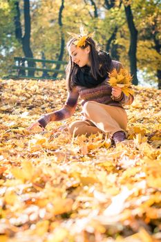 beautiful girl in autumn Park keeps yellow leaves