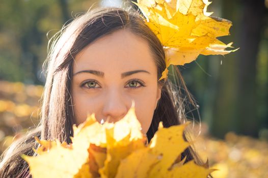 Portrait of a girl in autumn Park which keeps the yellow leaves