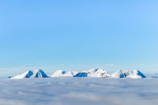 Snowcaped mountain tops peaking above the clouds
