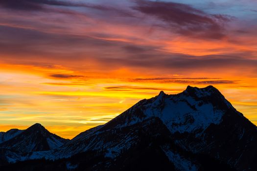 Red and orange sunset silhouettes a mountain peak
