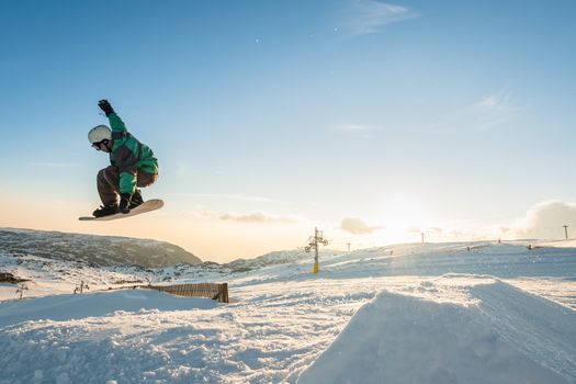 Snowboarder executing a radical jump against sunset sky.