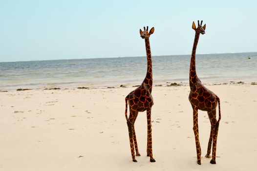 Couple of giraffes carving exposed on the white sandy beach of Bamburi in Mombasa, Kenya