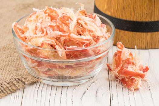 Dried squid in a glass bowl on old wooden table. Selective focus.