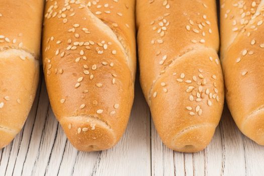 Bun with sesame seeds on old white wooden table. Selective focus.