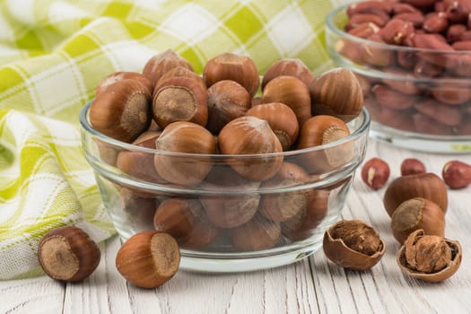 Hazelnut in a glass bowl on the old wooden table.  Selective focus. 