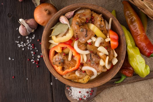 Marinated chicken in a clay bowl on old table. Top view.