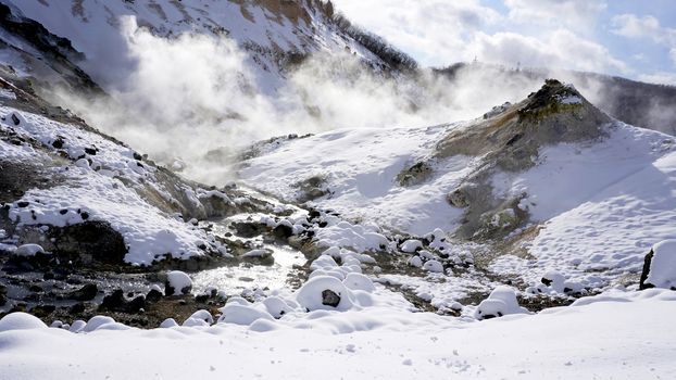 Closeup snow stone and stream in the mist Panorama Noboribetsu onsen snow winter national park in Jigokudani, Hokkaido, Japan