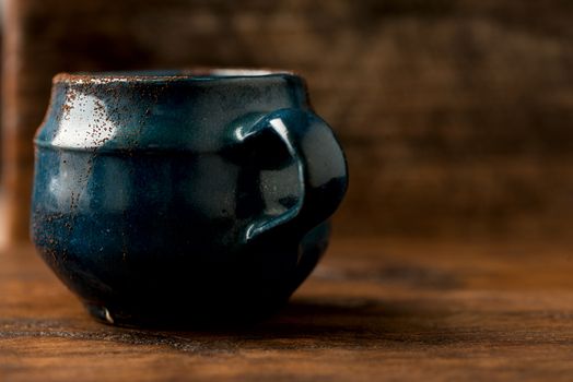 Coffee in grunge blue clay cup on rustic wooden background