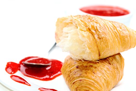 Croissant and jam on white plate close up