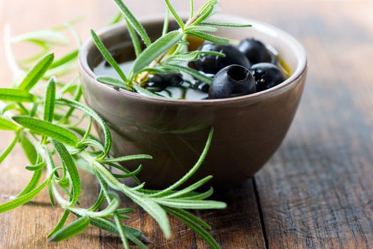 Black olives in clay bowl and rosemary set