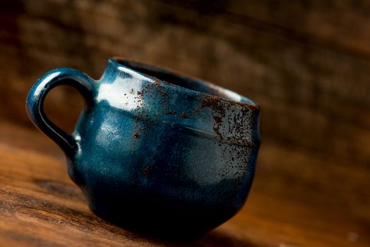 Coffee in grunge blue clay cup on rustic wooden background