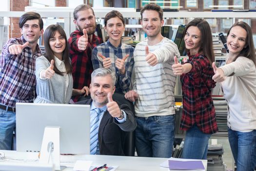 Group of business people in casual clothes with thumbs up at the office