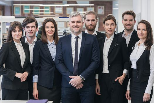 Group of friendly businesspeople with male mature leader in office