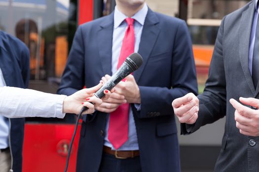 Reporter holding microphone, conducting press interview. News conference.