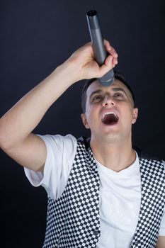 Young black-haired man dressed in black and white performs singing to microphone