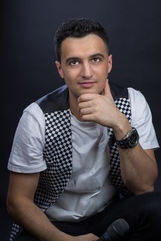 Young black-haired man dressed in black and white poses singing to microphone