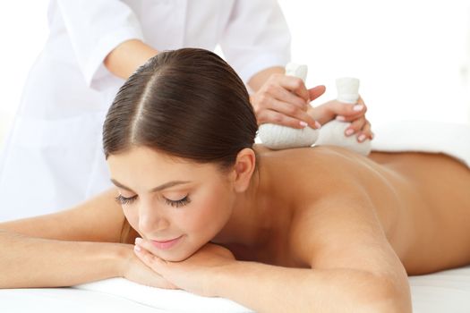 Woman in spa getting massage with herbal balls