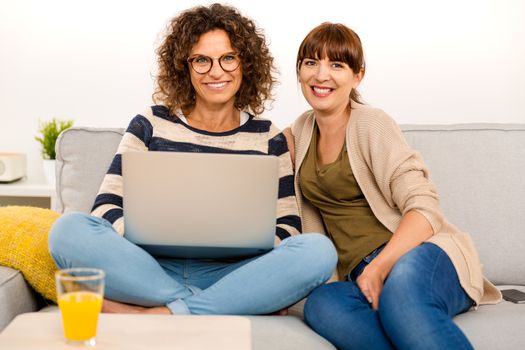 Two beautiful women at home working with a laptop