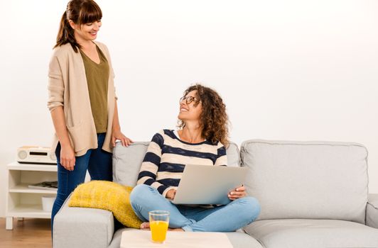 Two beautiful women at home working with a laptop