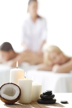 Spa massage tools and women getting massage on background