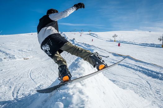 Snowboarder executing a radical slide against blue sky.