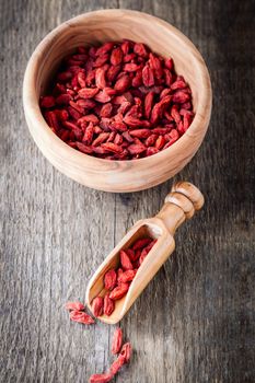 Dried goji berries with a wooden spoon on a table